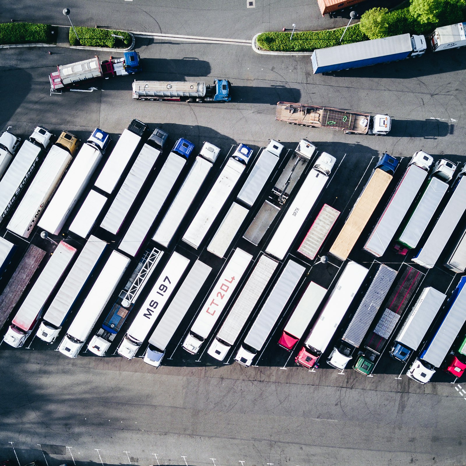 Vista aérea de uma frota de caminhões estacionados em um pátio logístico. Foto: Nigel Tadyanehondo / Unsplash