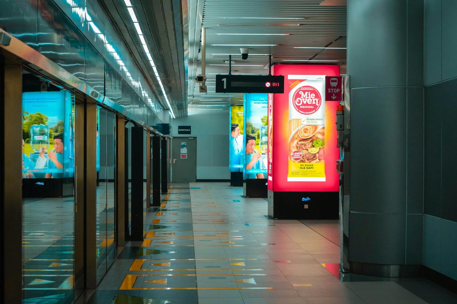 Corredor de estação com painel de mídia digital iluminado em vermelho. Foto: Syahril Fadillah / Unsplash