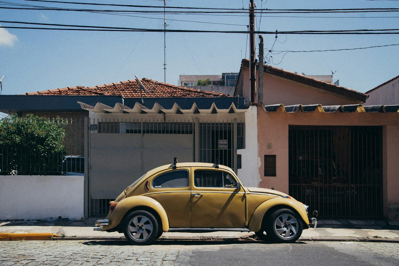 Vista aérea de um bairro residencial: casas de um lado da rua e carros estacionados na porta. Foto: Diwei Zhu / Unsplash