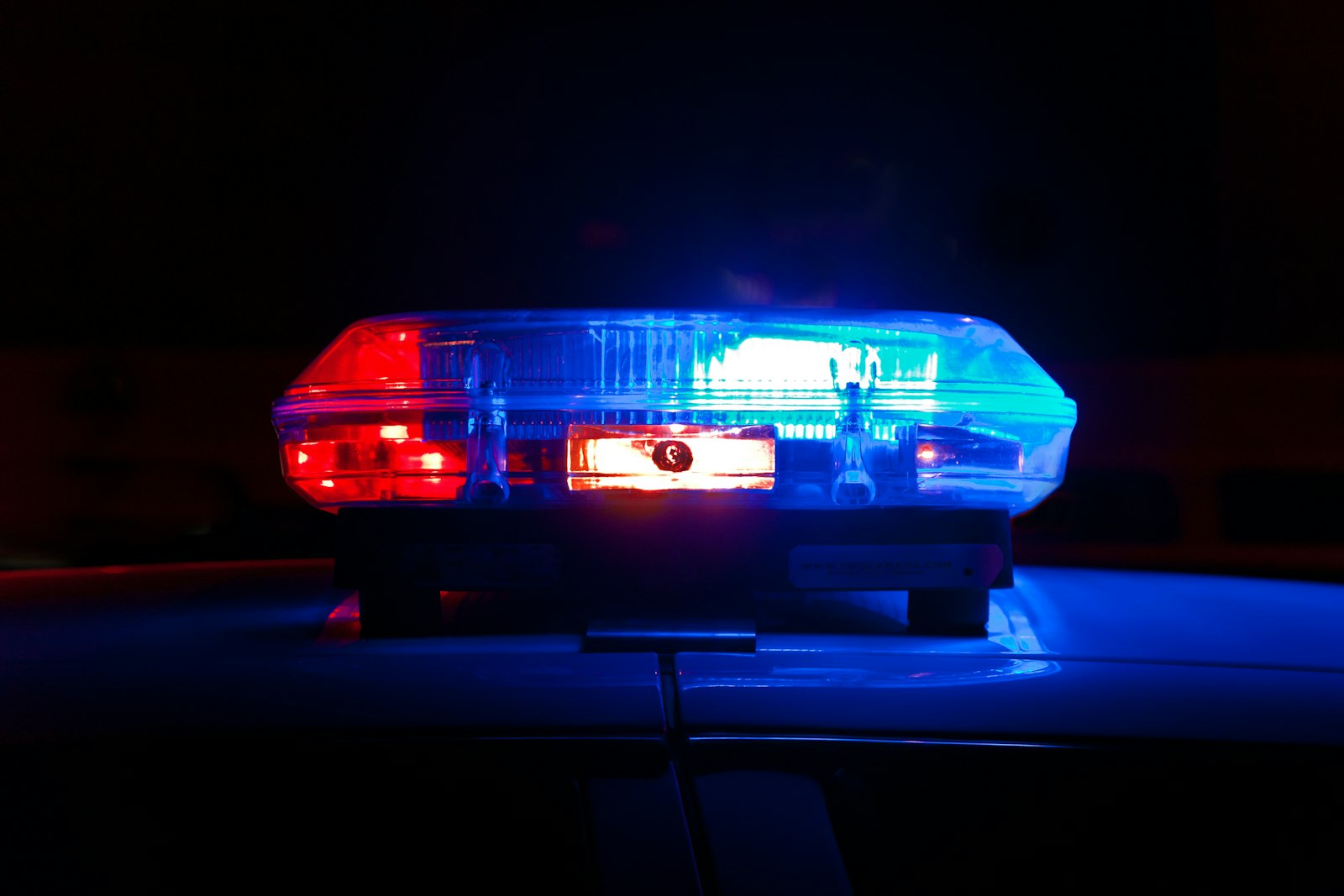 Giroflex de viatura policial aceso à noite, em vermelho e azul. Foto: Scott Rodgerson / Unsplash
